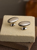 Nickel silver oval cabinet knobs on stone block, top-angle view
