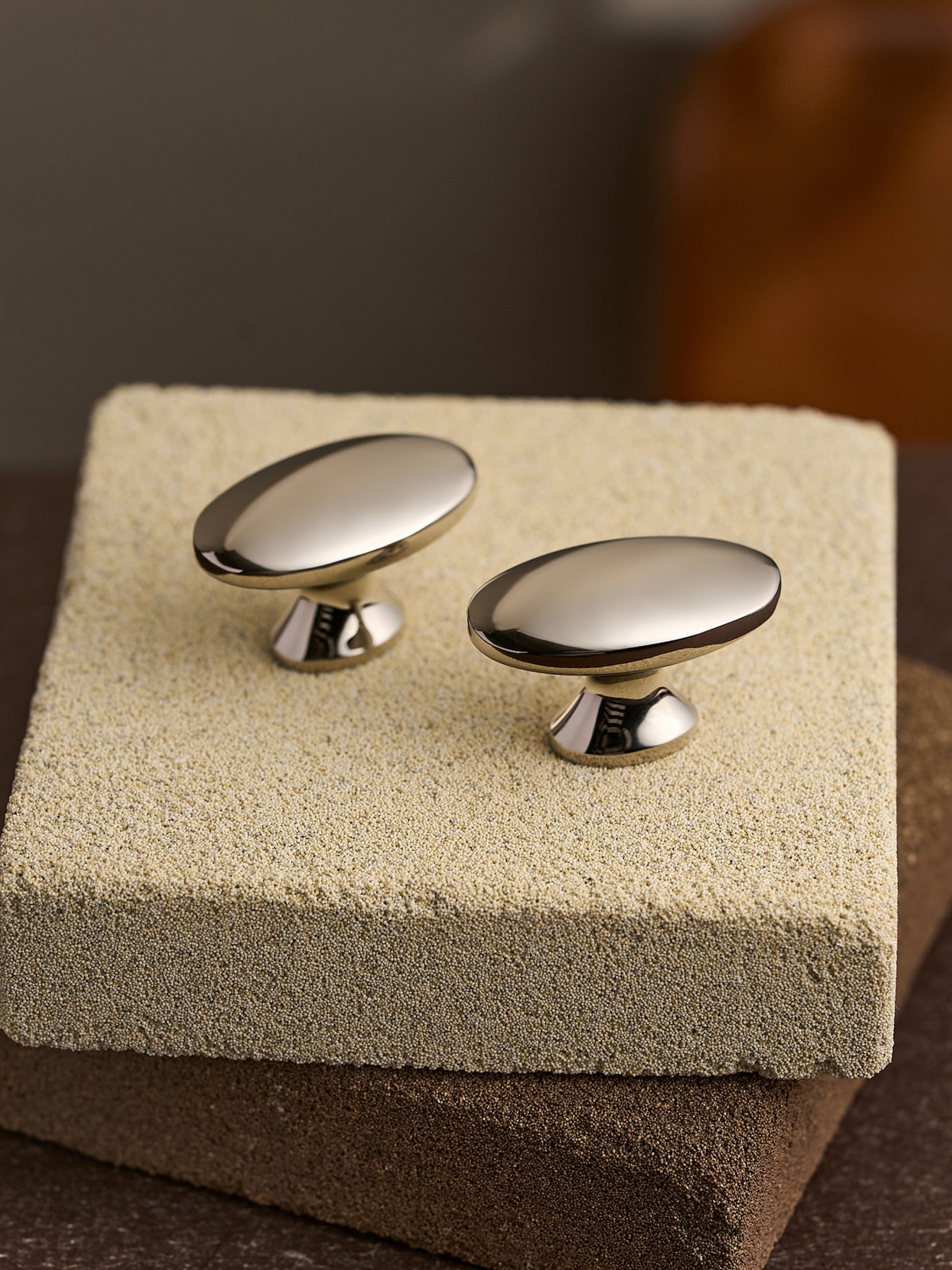 Nickel silver oval cabinet knobs on stone block, top-angle view