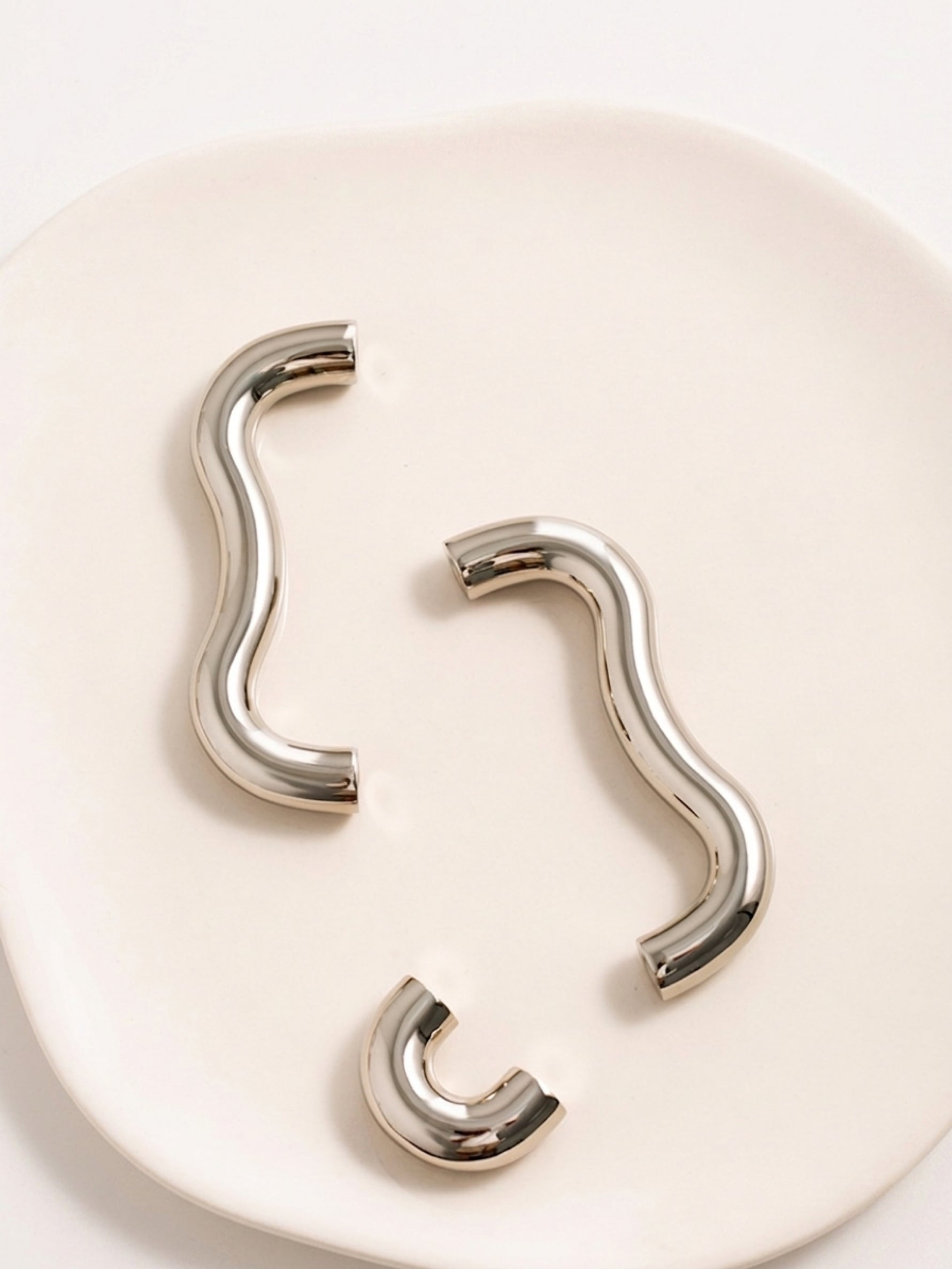 Nickel chrome wavy pulls and arch knobs from above showing curved silhouette