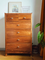Polished chrome wave star knobs on mid-century wood dresser drawers with plant and picture frame styling