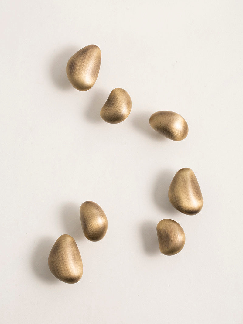 Brushed brass pebble knobs top view — organic sculptural cabinet hardware