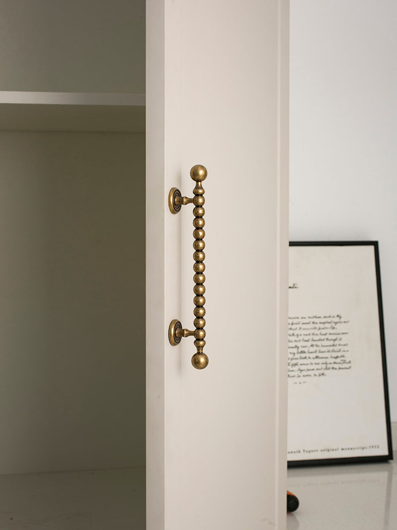 Close-up of a antique brass door handle on a white door with a framed picture in the background.