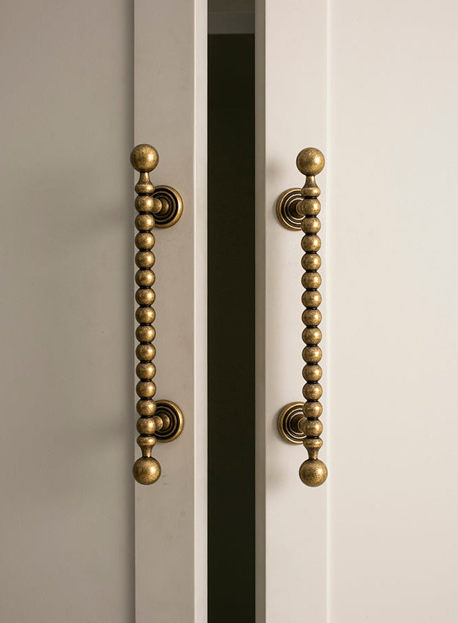 Close-up of a cabinet with decorative antique brass handles on a neutral background