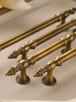 Close-up of ornate brushed brass handles on a light background