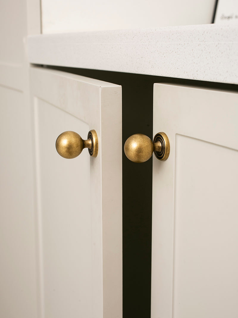 Close-up of white cabinet doors with antique brass knobs