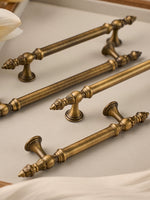 Set of ornate brushed brass cabinet handles on a light background