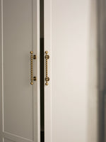 Close-up of a door with decorative antique brass handles on a neutral background