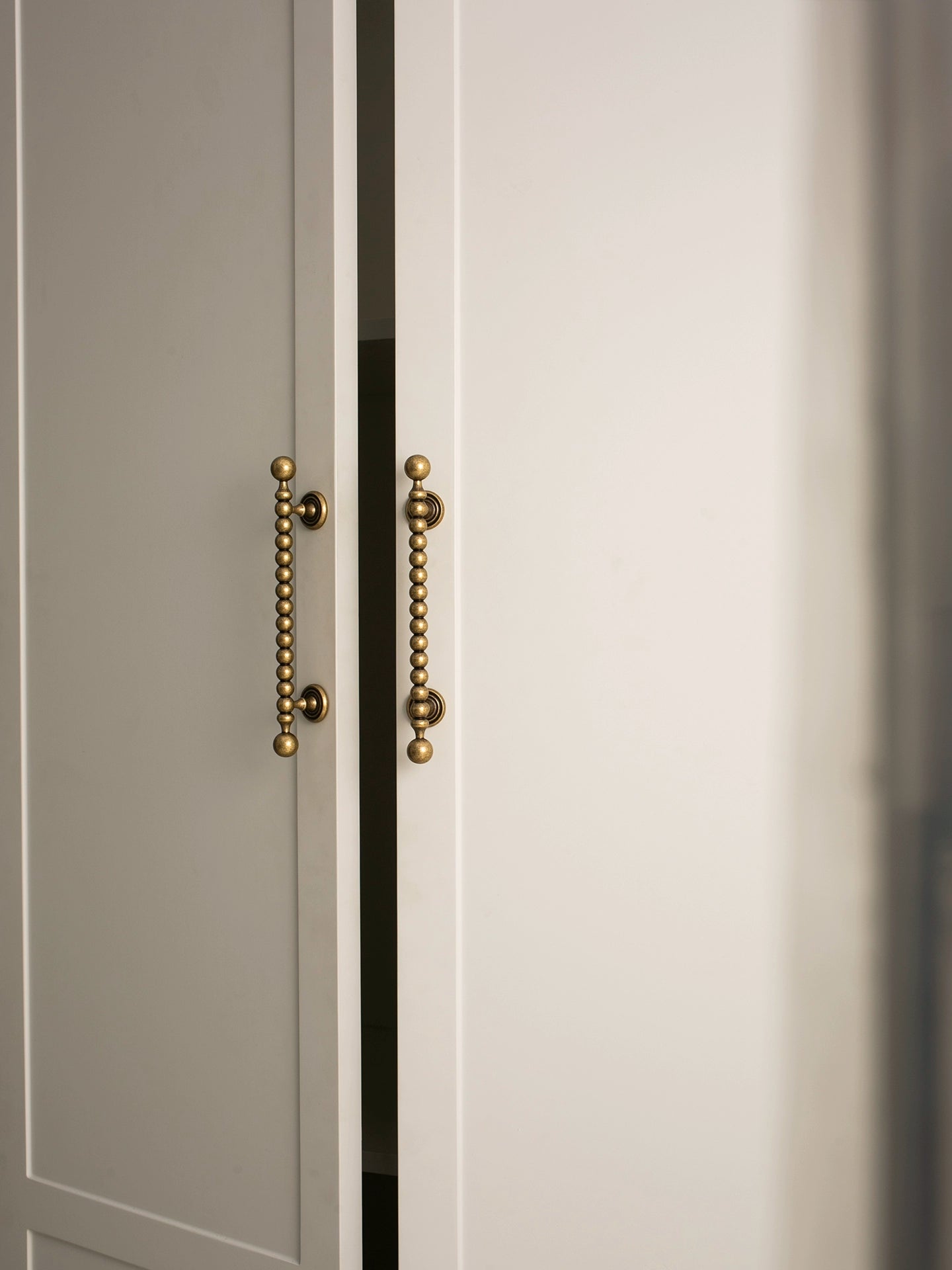 Close-up of a door with decorative antique brass handles on a neutral background