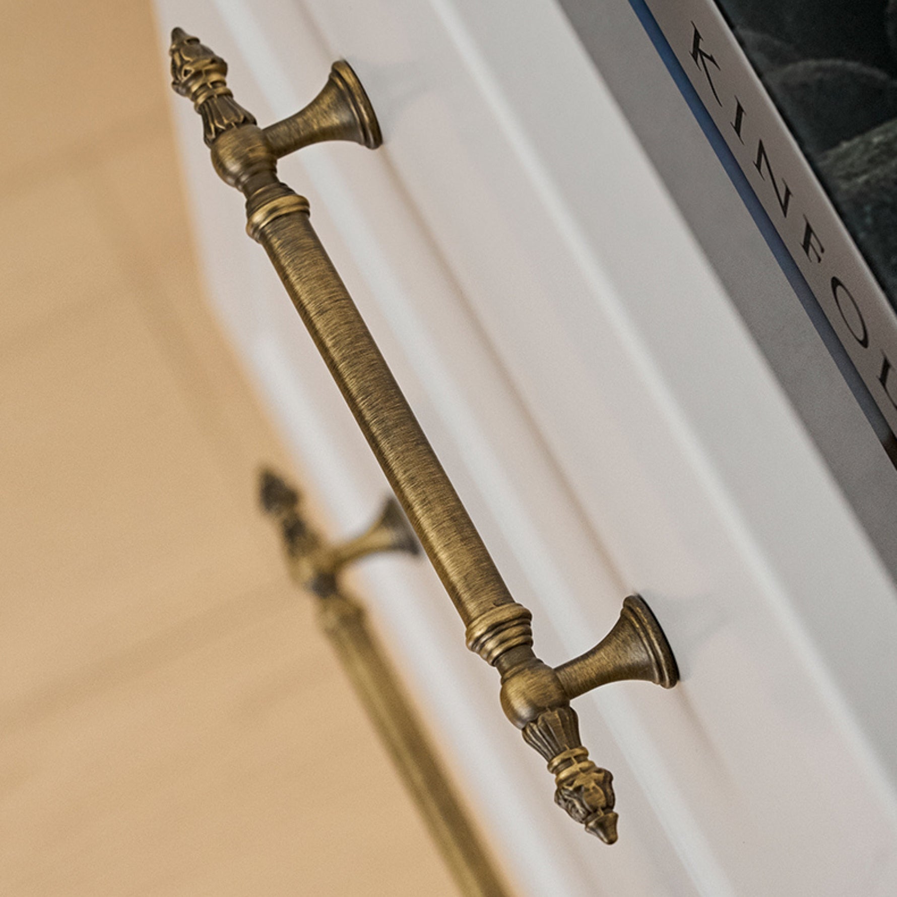 Decorative brushed brass handle on a white surface with 'KINFOLK' branding.