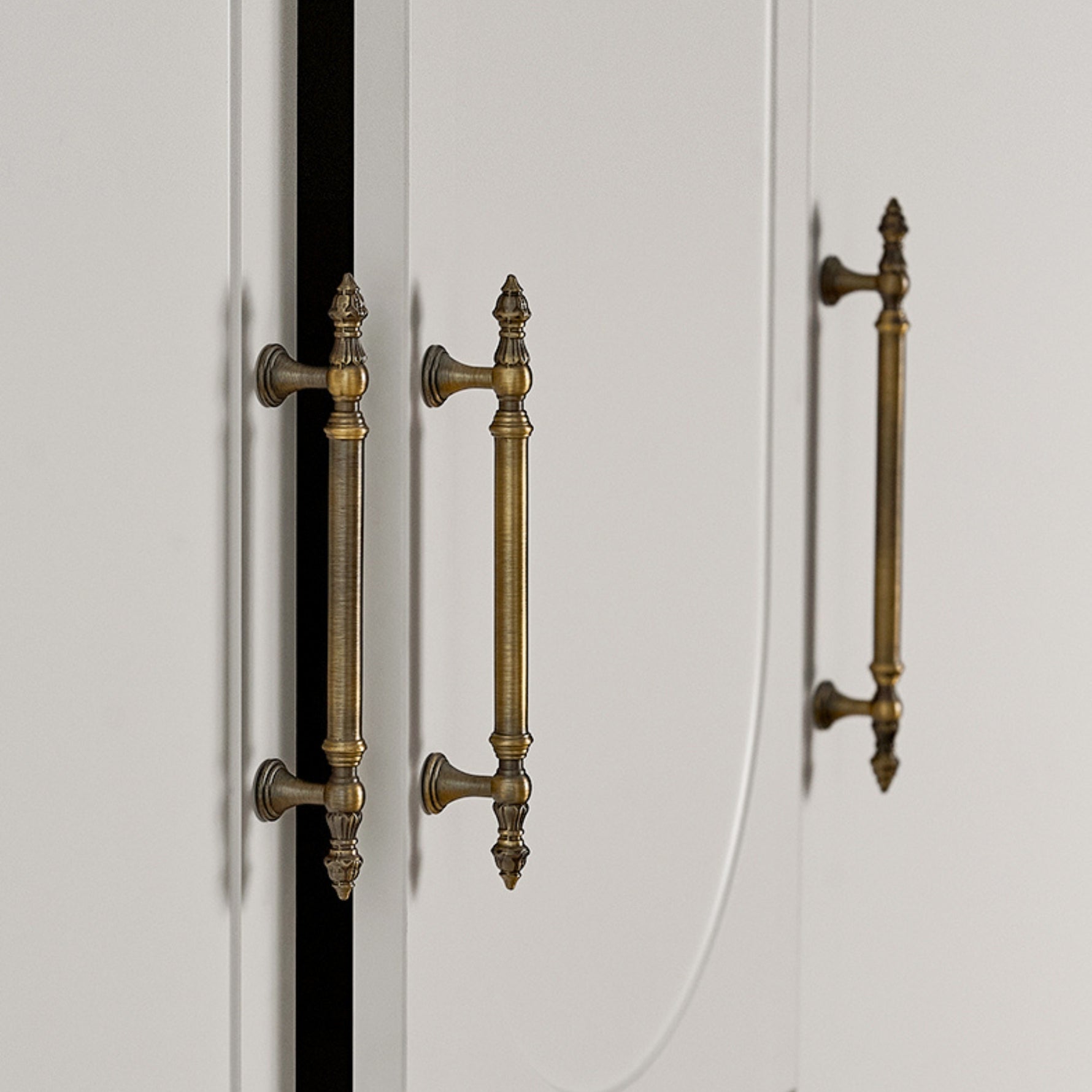 Close-up of white cabinet doors with brushed brass handles on a neutral background