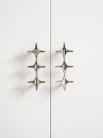 Two polished chrome star cross double pulls on white cabinet doors, front view